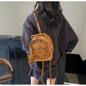 Detail view of brown lychee leather backpack with graffiti patterns and bear charm