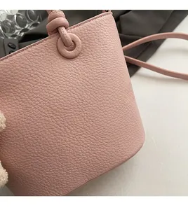 Dettaglio della borsa a secchiello rosa con trama litchi e manico annodato creativo