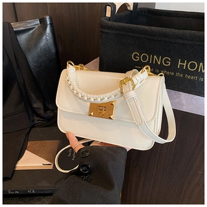 Détail du sac bandoulière crème avec poignée tressée et fermoir rotatif en métal doré