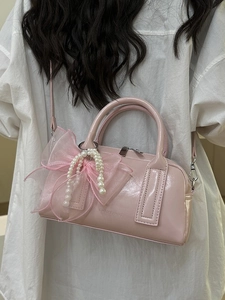 Sac Boston en cuir verni rose avec nœud en résille et perle montré de dos avec bandoulière