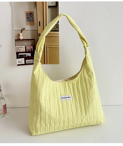 Detail of light yellow pleated fabric texture and white logo label on the tote bag