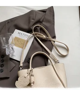 Détail du sac cabas en cuir grainé blanc cassé avec bandoulière réglable et breloque chien