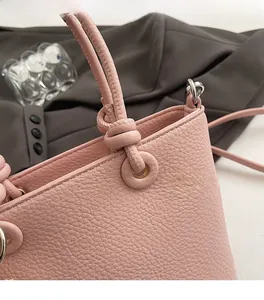Dettaglio del manico in pelle martellata con cuciture precise su una borsa a secchiello