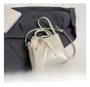 Detailed shot of white bucket bag with pearl bow, ribbon, and cute doll pendant accessory