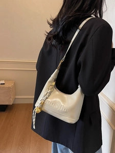 Creamy white leather half-moon shoulder bag with woven pendant and adjustable strap