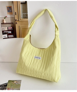 Detail of light yellow tote bag featuring unique crinkled fabric texture and brand label