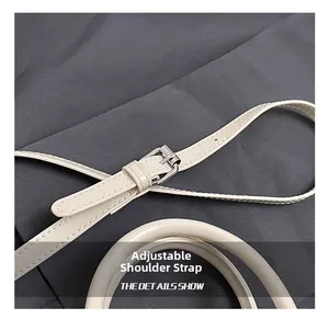 Detail show of adjustable shoulder strap with silver buckle and fine stitching on cream bag