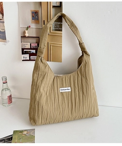 Close-up of light brown pleated tote bag with Duociyuan Bag logo on a white fabric surface