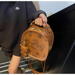 Detail of brown lychee leather backpack featuring vintage bear prints and bear charm