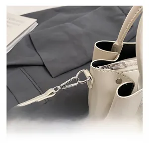 Close-up of detachable silver metal hook and fine shoulder strap on cream bucket bag