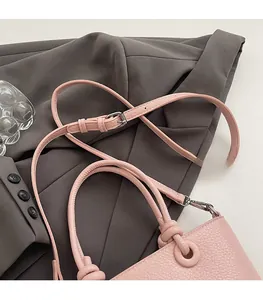 Dettaglio borsa a secchiello rosa in pelle martellata con manico a nodo e tracolla