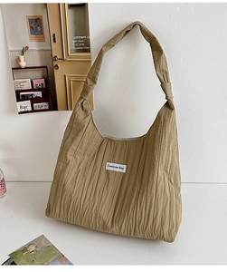 Detail of khaki pleated fabric shoulder bag with broad strap and branded label