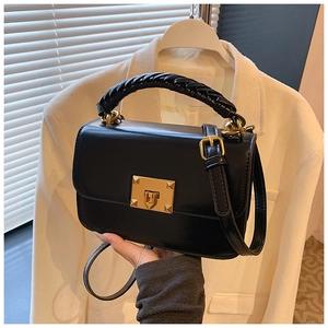 Détail du sac bandoulière en cuir noir avec boucle dorée et poignée tressée