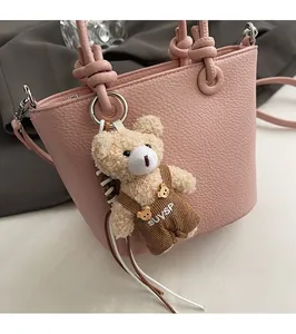 Dettaglio di un ciondolo a forma di orsetto in peluche su una borsa a secchiello in pelle rosa