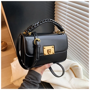 Détail du sac en cuir noir avec poignée tressée et boucle en métal doré chic