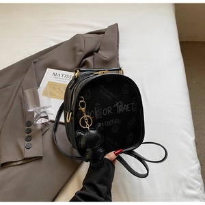 Macro detail of black leather backpack with white graffiti text and golden metal zipper