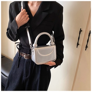 Detail of silver metallic mini bag featuring curved top handle and smooth glossy finish