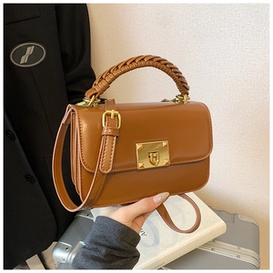 Détail du sac en cuir caramel avec poignée tressée et fermoir rotatif doré