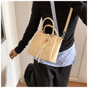 Cream bucket bag detail showing pearl strap and premium leather texture on a model