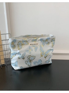 Artistic woven canvas makeup bag featuring elegant blue and gold butterfly patterns with zipper