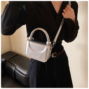 Close-up of a silver metallic mini square bag with glossy texture and fixed top handle