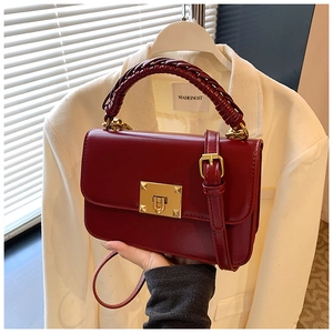 Détail du sac bandoulière bordeaux avec poignée tressée et fermoir doré carré