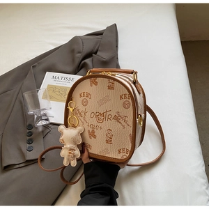 Close-up of retro bear print and premium textured leather on a chic beige crossbody bag