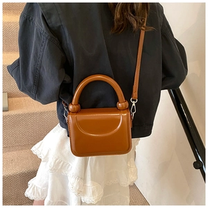 Caramel brown leather mini bag with beaded handle detail shown on a chic outfit