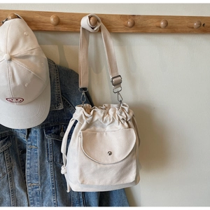 Sac seau en toile à cordon avec bandoulière réglable à côté d'une veste en jean et casquette