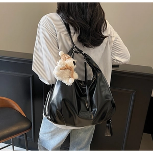 Détail d'un grand sac cabas noir en cuir avec une peluche d'ours blanc sur l'épaule