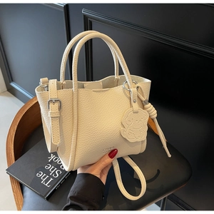 Détail du sac cabas en cuir crème avec charm ours mignon et finitions argentées
