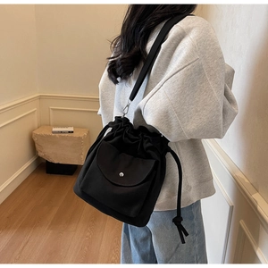 Détail du sac seau en toile noire avec cordon de serrage et poche à bouton pression argent