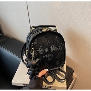 Close-up of black leather backpack with graffiti prints and a cute bear keychain charm