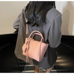 Sac seau rose à texture litchi avec logo embossé porté par un mannequin pour taille