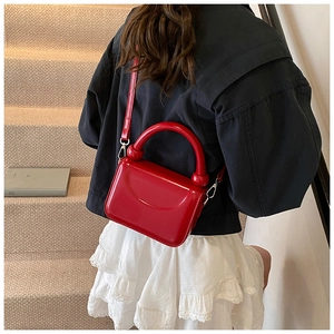 Detail of red glossy patent leather handbag with silver hardware and ring handle