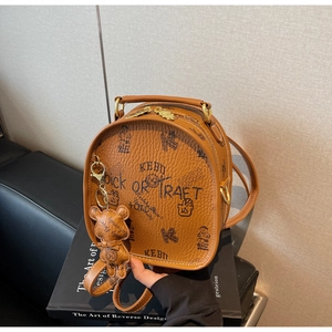 Close-up of retro brown round backpack with embossed bears and golden hardware detail