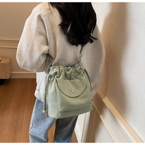 Détail du sac seau en toile vert clair avec fermeture à cordon et poche avant à rabat