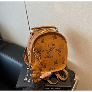 Detailed view of brown litchi leather backpack with bear prints and gold zippers