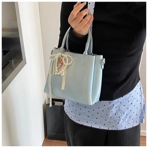 Close-up of light blue bucket bag featuring pearl bow and cute girl pendant detail