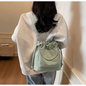 Détail du sac seau en toile vert menthe avec cordon, poche à rabat et bandoulière tissée