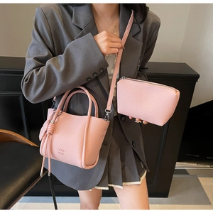 Détail du sac à main en cuir grainé rose avec pompon et petite pochette assortie