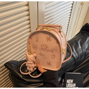 Close-up of pink leather backpack with cartoon bear prints and teddy bear charm