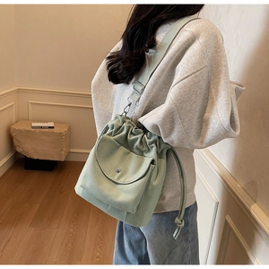 Détail du sac seau en toile vert clair avec cordon de serrage et bandoulière réglable