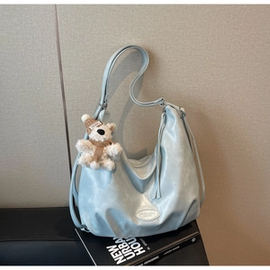 Détail du sac fourre-tout en cuir souple bleu clair avec fermeture éclair et breloque ours