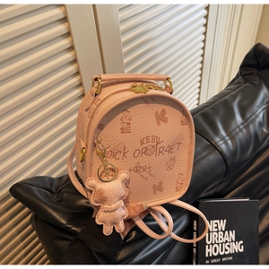 Detail of light pink mini backpack with graffiti print and cute bear charm attachment