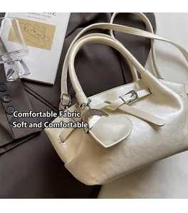 Detail der cremefarbenen Beuteltasche mit Herzanhänger und verstellbarer Schnalle