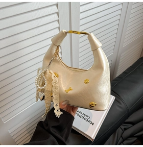Λεπτομέρεια της κρεμ δερμάτινης τσάντας με χρυσά αρκουδάκια και μενταγιόν από πέρλες