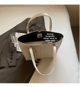 Detail of the magnetic buckle closure and internal zipper pocket on cream tote bag
