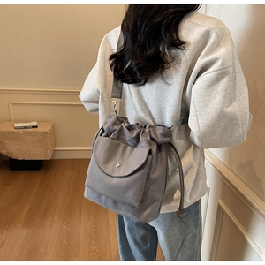 Vue arrière d'un mannequin portant un sac seau gris en toile avec bandoulière réglable