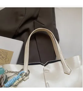 Detail of comfortable off-white tote bag handle with blue woven rope and charm decoration